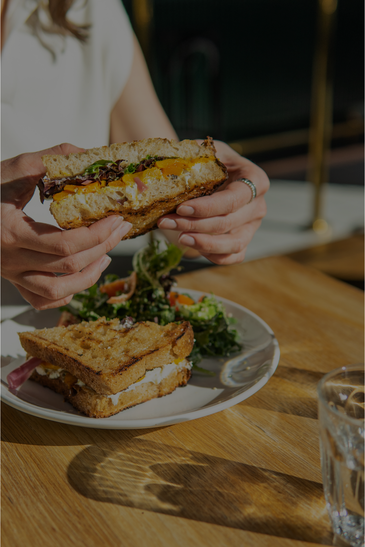 A closeup image of a customer holding half of a butternut squash and ricotta sandwich.